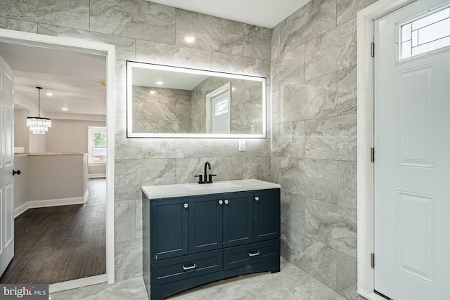 bathroom featuring vanity, tile walls, and an inviting chandelier