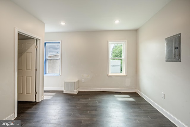 spare room with electric panel and dark wood-type flooring