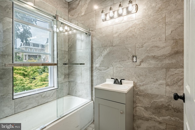 bathroom featuring combined bath / shower with glass door and vanity