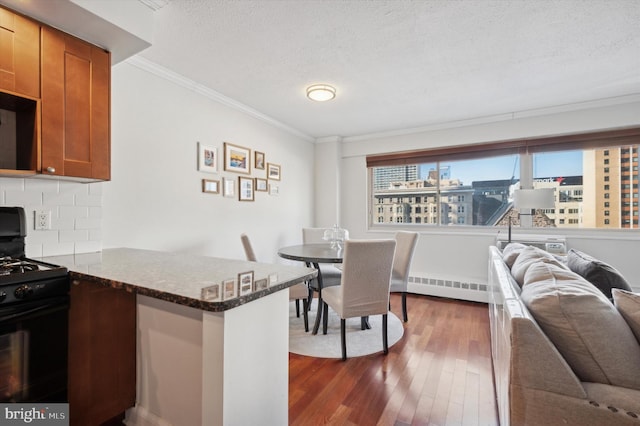 dining room with a baseboard heating unit, dark wood-type flooring, crown molding, and a textured ceiling