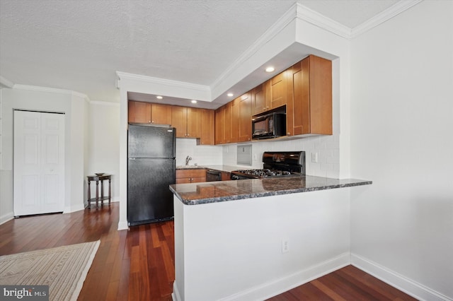 kitchen featuring black appliances, kitchen peninsula, dark stone counters, and ornamental molding