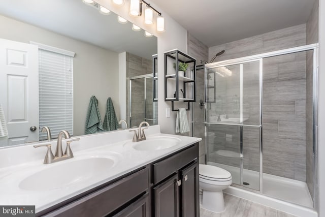 bathroom featuring a shower with shower door, toilet, and vanity