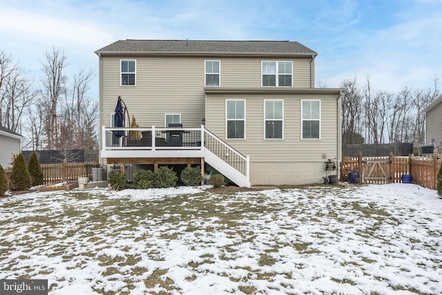 snow covered rear of property with a deck