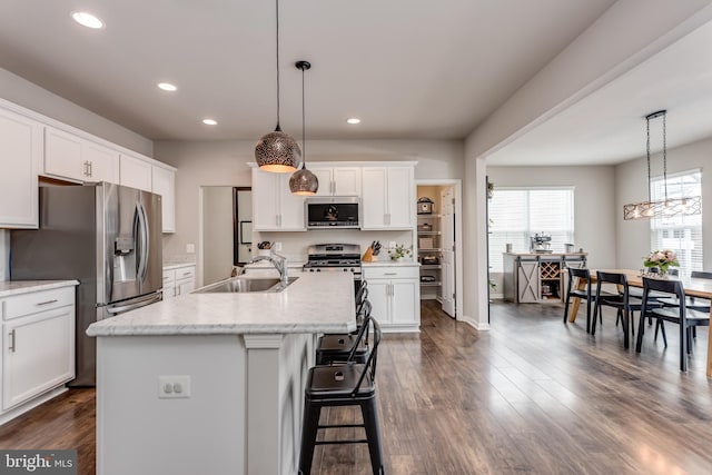 kitchen featuring a center island with sink, appliances with stainless steel finishes, hanging light fixtures, white cabinets, and sink