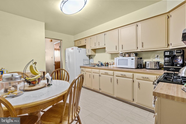 kitchen featuring sink, cream cabinetry, and white appliances