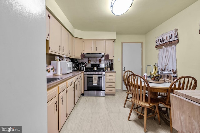 kitchen featuring sink, cream cabinetry, gas stove, and tasteful backsplash