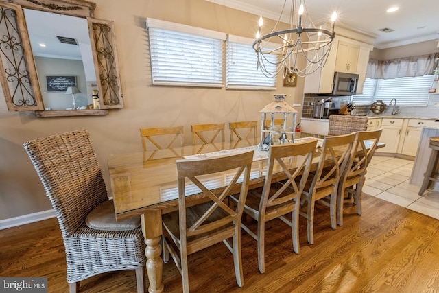 dining space with light wood-type flooring, a chandelier, and ornamental molding