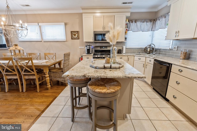 kitchen with pendant lighting, a kitchen island, stainless steel appliances, sink, and light tile patterned floors