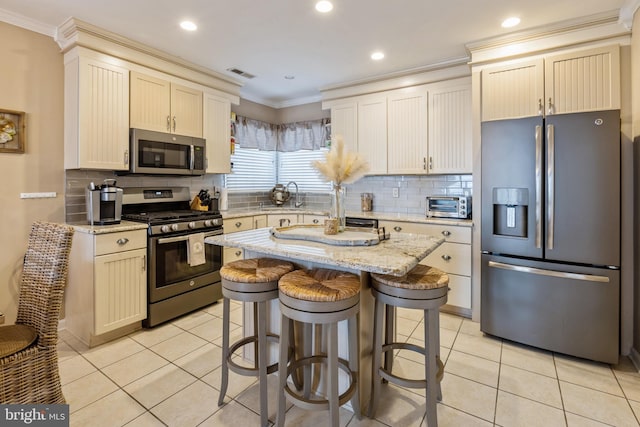 kitchen with tasteful backsplash, a center island, light tile patterned flooring, light stone countertops, and stainless steel appliances