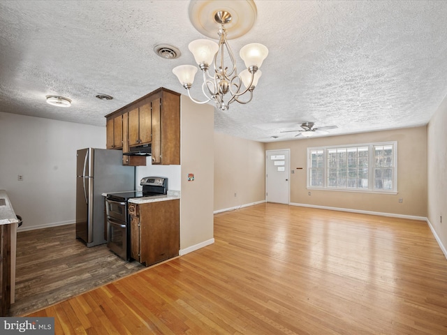 kitchen with light wood-type flooring, stainless steel appliances, ceiling fan with notable chandelier, and hanging light fixtures