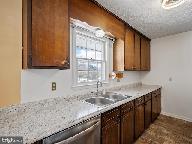 kitchen with sink, a textured ceiling, stainless steel dishwasher, and dark hardwood / wood-style floors