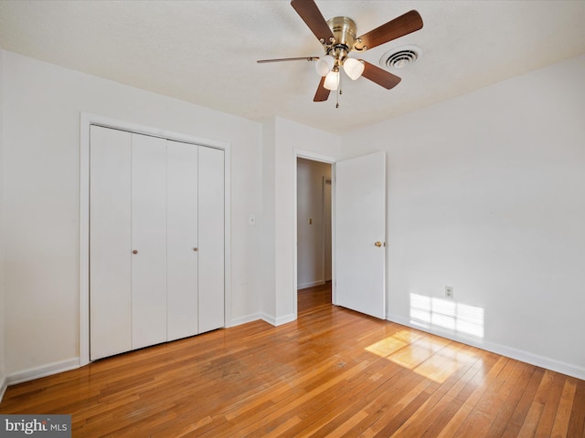 unfurnished bedroom with ceiling fan, a closet, and light wood-type flooring