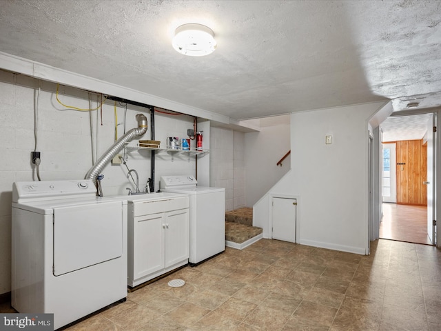 laundry room featuring a textured ceiling, cabinets, and separate washer and dryer