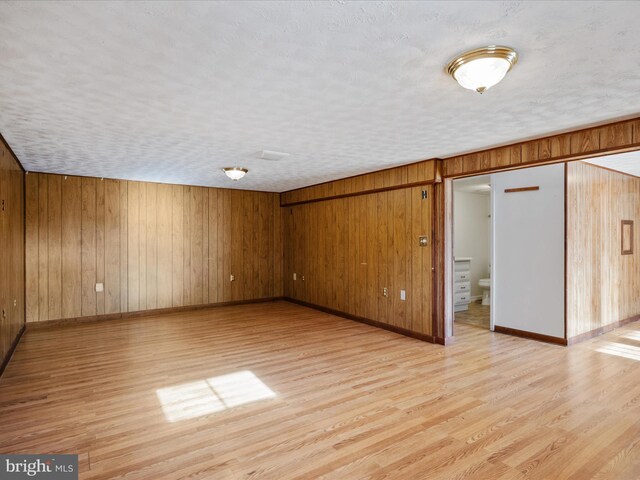 interior space with wood walls, light hardwood / wood-style floors, and a textured ceiling