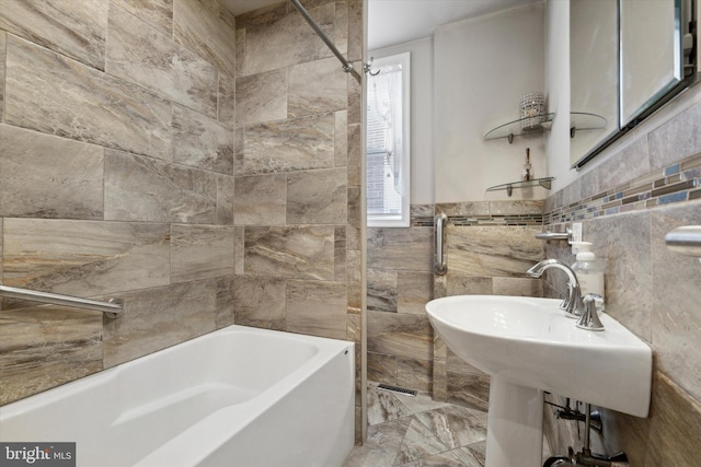 bathroom with shower / bath combination, tile walls, and sink