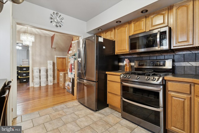 kitchen with light tile patterned floors, stainless steel appliances, a chandelier, and backsplash