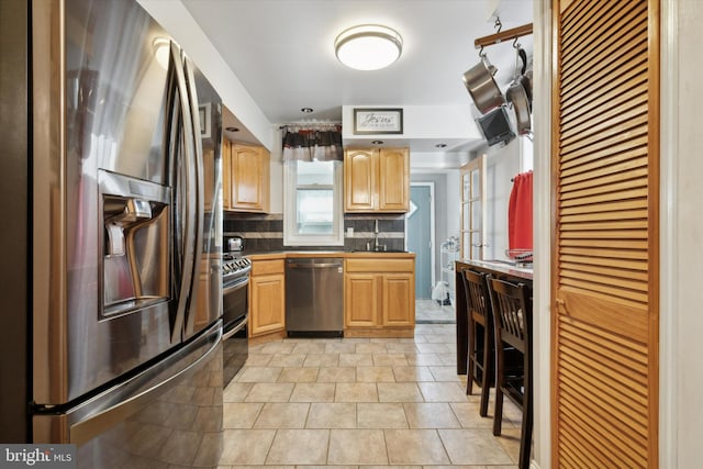 kitchen featuring stainless steel appliances, tasteful backsplash, light brown cabinetry, sink, and light tile patterned floors