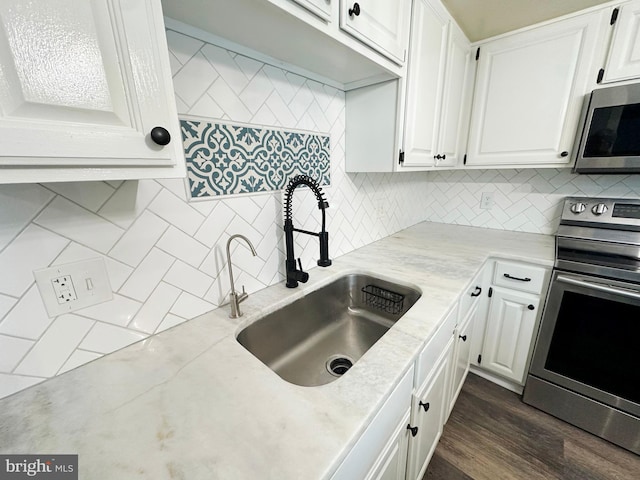 kitchen featuring white cabinets, stainless steel appliances, tasteful backsplash, sink, and dark hardwood / wood-style floors