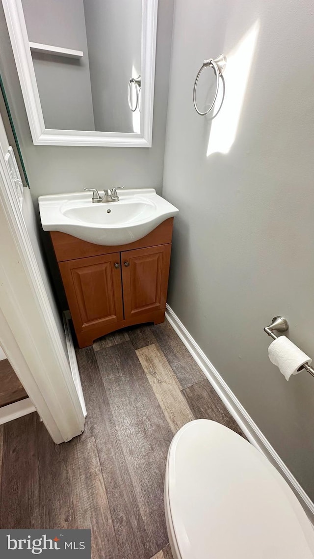 bathroom featuring toilet, hardwood / wood-style floors, and vanity