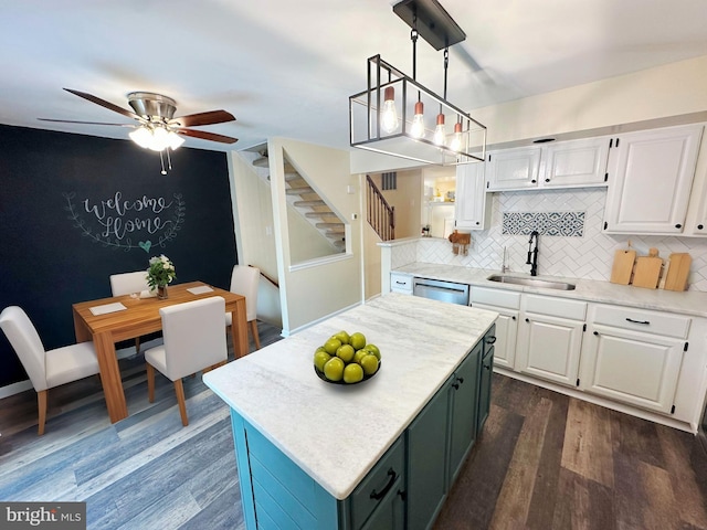 kitchen featuring decorative light fixtures, a center island, decorative backsplash, sink, and white cabinetry