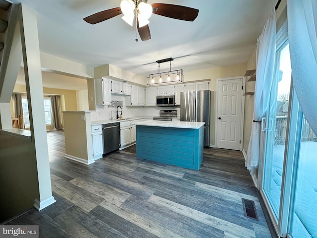 kitchen featuring white cabinets, a kitchen island, stainless steel appliances, tasteful backsplash, and sink