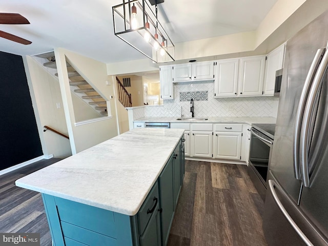 kitchen with appliances with stainless steel finishes, white cabinetry, a kitchen island, and sink