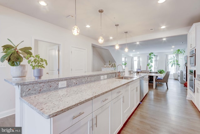 kitchen featuring a large island, sink, pendant lighting, white cabinetry, and light stone countertops