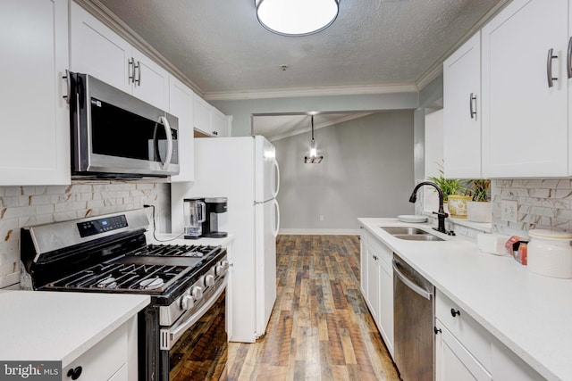 kitchen with sink, white cabinets, appliances with stainless steel finishes, and ornamental molding