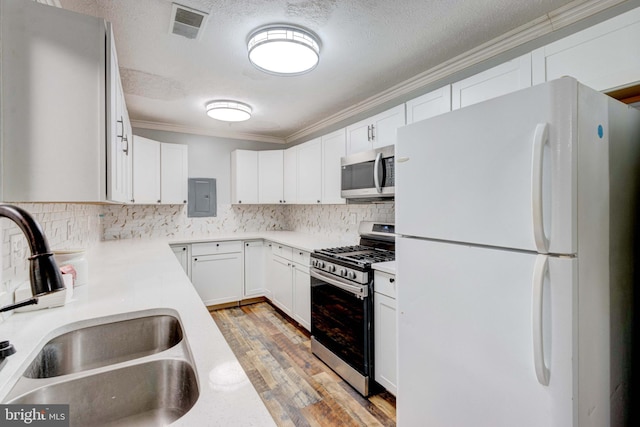 kitchen with a textured ceiling, white cabinets, appliances with stainless steel finishes, tasteful backsplash, and sink