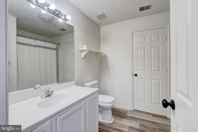 bathroom featuring toilet, hardwood / wood-style floors, a textured ceiling, curtained shower, and vanity