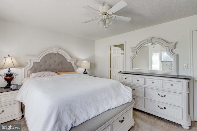 bedroom featuring ceiling fan, light colored carpet, and a textured ceiling