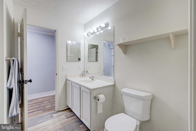 bathroom featuring wood-type flooring, toilet, a textured ceiling, and vanity