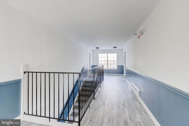 hall with light hardwood / wood-style flooring and a textured ceiling