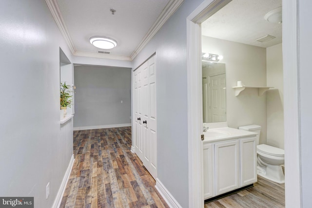 hall featuring sink, a textured ceiling, dark hardwood / wood-style floors, and crown molding