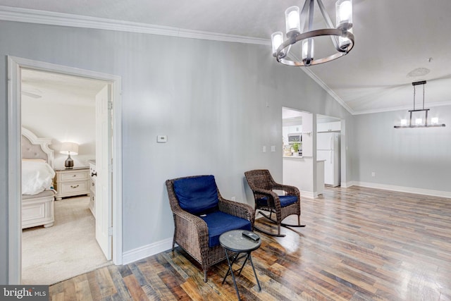 sitting room featuring vaulted ceiling, an inviting chandelier, hardwood / wood-style flooring, and crown molding