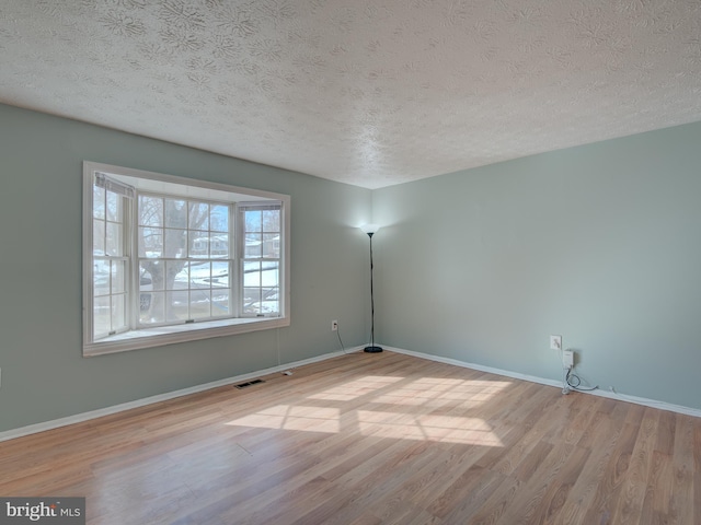 empty room featuring a textured ceiling and light hardwood / wood-style flooring