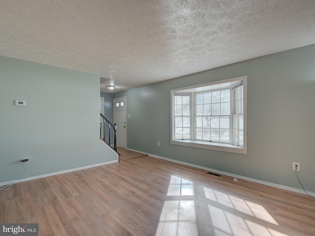 empty room with light hardwood / wood-style floors and a textured ceiling