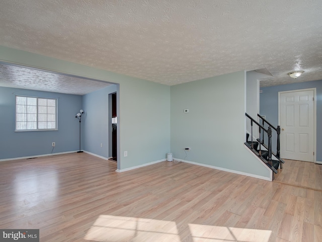 spare room with a textured ceiling and light hardwood / wood-style flooring