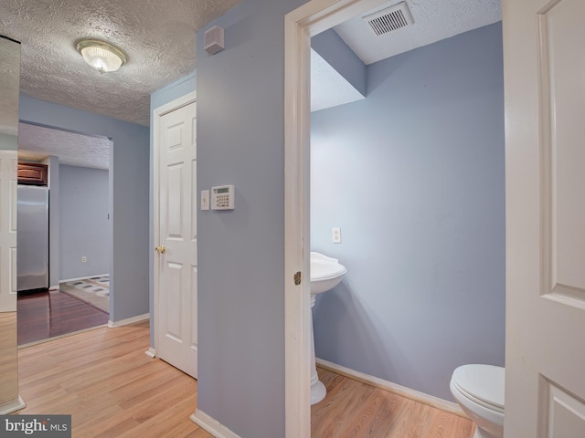 bathroom featuring hardwood / wood-style floors, a textured ceiling, and toilet