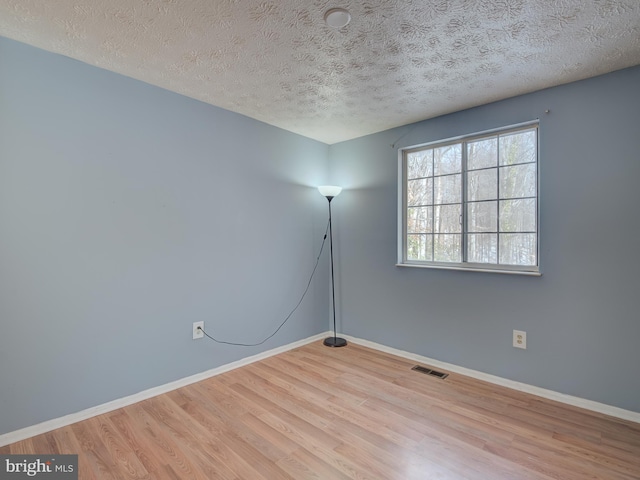 unfurnished room with a textured ceiling and light hardwood / wood-style flooring