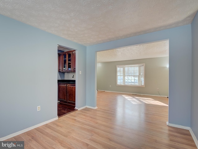 unfurnished living room with a textured ceiling and light wood-type flooring