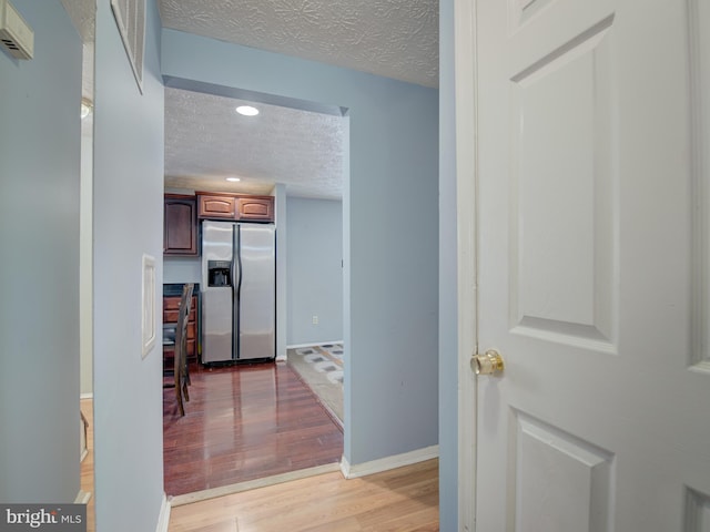 corridor featuring light hardwood / wood-style floors and a textured ceiling