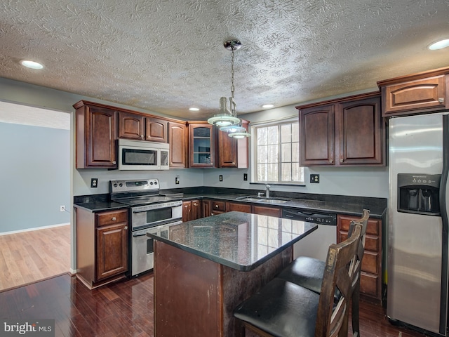 kitchen featuring a center island, a textured ceiling, sink, stainless steel appliances, and dark hardwood / wood-style floors