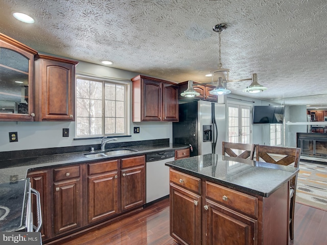 kitchen with dark wood-type flooring, sink, appliances with stainless steel finishes, and a center island