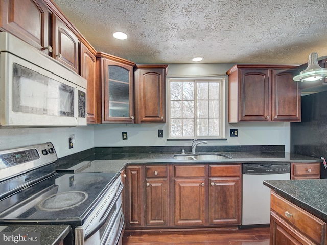 kitchen with a textured ceiling, dark stone counters, sink, dark hardwood / wood-style flooring, and stainless steel appliances