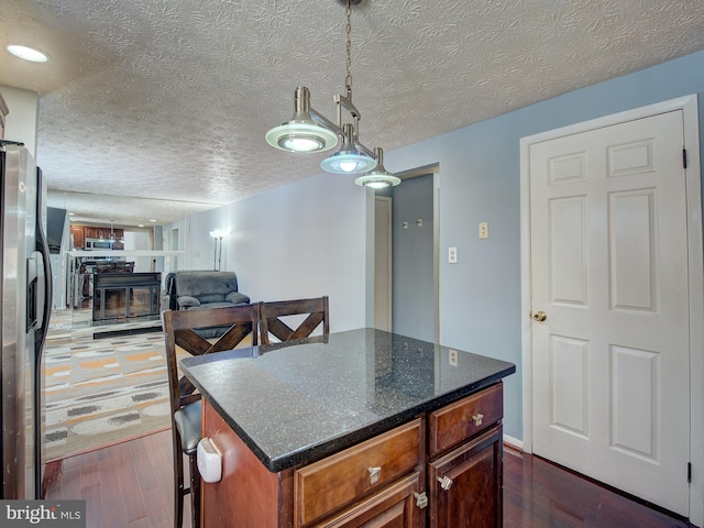 kitchen featuring a textured ceiling, dark hardwood / wood-style floors, stainless steel fridge with ice dispenser, and a kitchen island