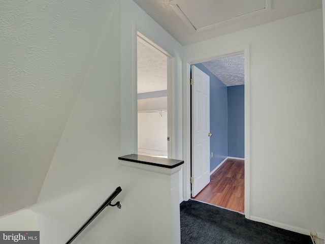 hall with carpet flooring and a textured ceiling