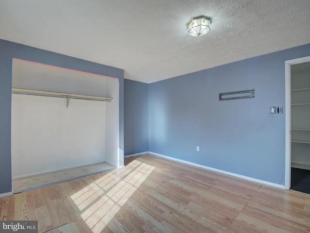 unfurnished bedroom featuring light hardwood / wood-style floors, a textured ceiling, and a closet