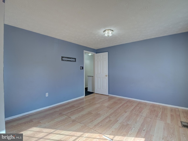 unfurnished room with light hardwood / wood-style floors and a textured ceiling