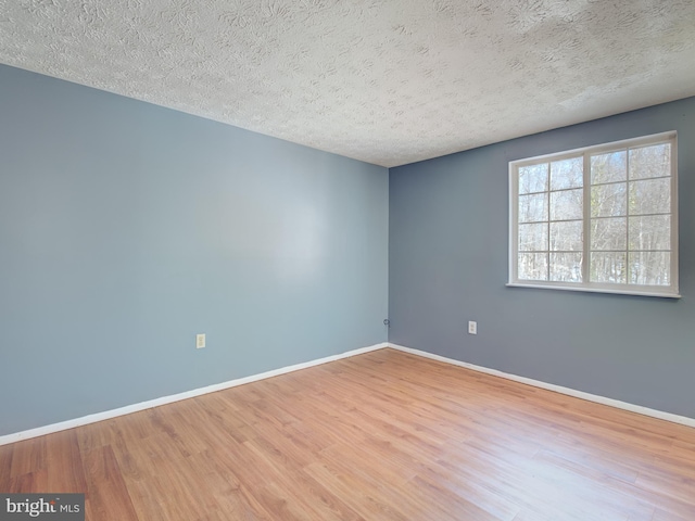 unfurnished room with light wood-type flooring and a textured ceiling